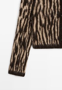 Cardigan marrone e crema a fantasia, realizzato in tessuto morbido e strutturato con una finitura pelosa e bottoni neri sul davanti.