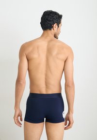 Marineblauwe boxershorts in een slim fit ontwerp met een zachte textuur, voorzien van een witte geborduurde logo op de achterkant.