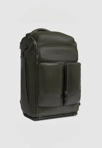 Zaino grande in pelle verde scuro con due tasche frontali con cerniera, texture liscia e manico superiore robusto. Presenta un design minimalista e cerniere.