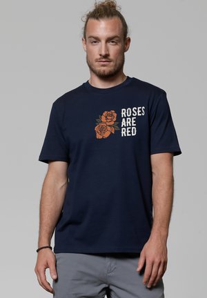 Navyblauwe katoenen t-shirt met een grafisch ontwerp van oranje rozen en witte tekst "ROZEN ZIJN ROOD," met korte mouwen en een ronde hals.