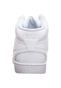 Vita Nike-sneakers i läder med vadderad krage, mönstrad textur och tydlig logotyp på hälen.