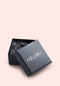 Scatola per gioielli nera con texture, con il coperchio leggermente aperto che rivela della carta velina nera all'interno. Il nome del marchio è stampato in bianco con un carattere corsivo nella parte frontale.