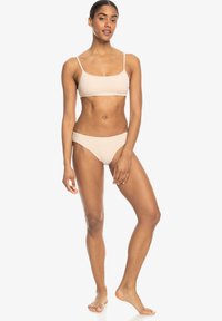 Lichtbruine geblokte bikini set met een cropped top en bijpassende high-waisted bikinibroekjes. Het materiaal lijkt glad met dunne bandjes.