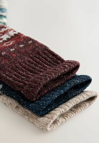 Három rétegbe rendezett gyapjú kesztyű: sötétburgundi, tengerészkék és világos bézs. Mindegyik redős mandzsettával és texturált mintával rendelkezik.