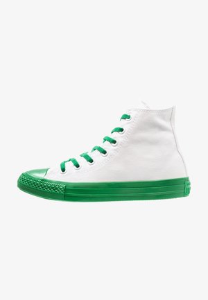 Weißer High-Top-Leinensneaker mit grünen Schnürsenkeln, grünem Gummizehenschutz und grünem Sohlenprofil, von der Seite gezeigt.