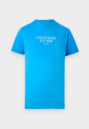 T-shirt bleu vif à manches courtes avec le texte blanc "CALVIN KLEIN EST. 1968" centré sur la poitrine.