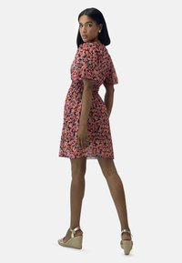 Kleid mit Blumenmuster in Pink mit mehrfarbigen Blumen, kurzen Puffärmeln, tailliertem Schnitt und knie-langer Saumlänge.