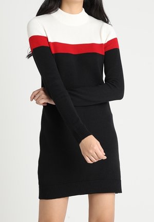 Gebreide jurk met hoge halslijn, kleurgeblokkeerd ontwerp in wit, rood en zwart, en ribgebreide manchetten en zoom. Lengte tot halverwege het bovenbeen.