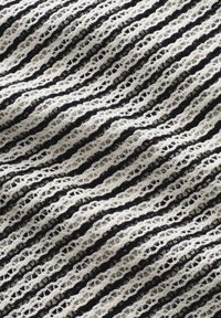 Zwart-wit gestreepte stof met een gestructureerd, open gebreid patroon, met afwisselend volle en holle lijnen, wat een golfachtige uitstraling creëert.