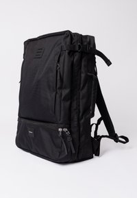Black backpack with a rectangular shape, featuring a textured fabric, adjustable straps, large front pocket, and dual zipper closures.