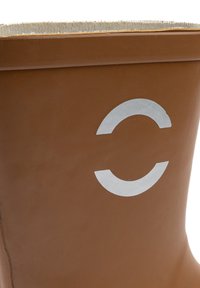 Pruun kummist saabas pehme beeži sisemise voodriga ja hõbedase ümmarguse logoga. Omab siledat, läikivat välist pinda.