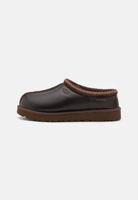 Brown leather clog with a thick, textured sole, stitched accent around the collar, and UGG branding on the side.
