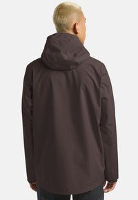 Brązowa wodoodporna kurtka z kapturem, gładka tekstura, długie rękawy; ma prosty krój i minimalistyczny design.