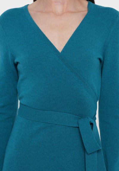 Grönblå omlottklänning i mjukt stickat tyg, med långa ärmar, V-ringning och ett tygbälte knutet i midjan.