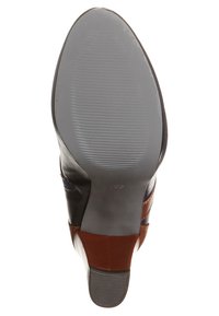 Suela de zapato de tacón que presenta una mezcla de cuero marrón, negro y azul marino. Superficie de goma texturizada con patrón acanalado y un leve tacón.