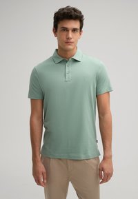 Mintgroene polo shirt gemaakt van zachte stof, met een kraag, drie knopen, korte mouwen en een klein logo op de borst.