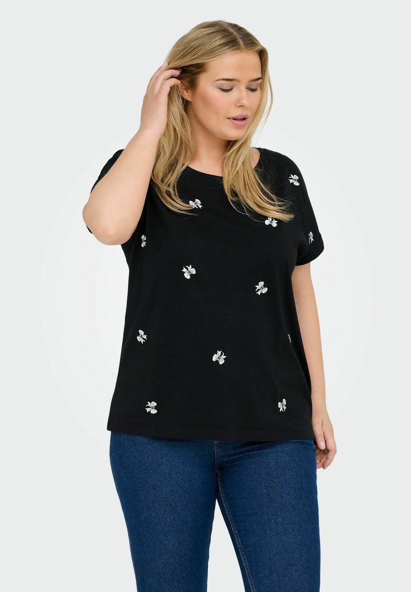 Svart skjorta i mjukt tyg, med vit blommig broderi som är utspridd över framsidan. Kortsleeves och en avslappnad passform.