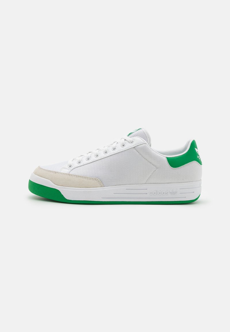 Baltas sneaks ar zaļiem akcentiem. Auduma un zamšādas augšdaļa, gumijas zole, plakana forma, apaļa purngala daļa un metāla acs šņorēm.