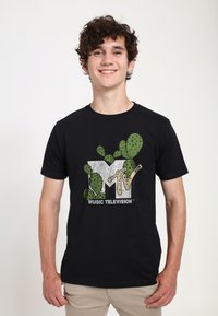 Černé bavlněné tričko s kaktusem inspirovaným logem MTV v zelené a béžové barvě, s textem "MUSIC TELEVISION" v bílé barvě dole.