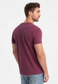 Kortærmet t-shirt i dyb burgunder bomuld, rund hals design, blød tekstur og et lille logo mærke i siden.