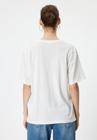 Effen wit katoenen t-shirt met korte mouwen, ontspannen pasvorm en ronde hals. De achterkant heeft een gladde textuur en verder geen extra details.