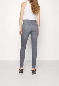 Jeans skinny de mezclilla gris con cintura alta, que cuentan con cinco bolsillos, una etiqueta en la parte trasera y un corte ajustado hasta el tobillo.