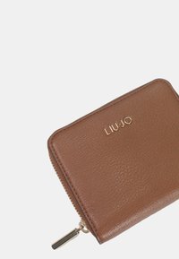 Cartera de cuero marrón con superficie texturizada, con el logo dorado "LIU-JO" en la parte frontal y un cierre de cremallera con un tirador de metal.