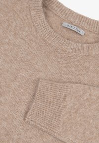 Beige gestrickter Pullover mit Rundhalsausschnitt, gerippten Bündchen und einer kleinen Brusttasche. Weicher Stoff und ein subtil gemischtes Muster im gesamten Pulli.