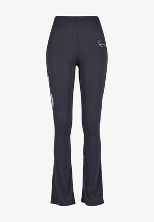 Črne rebraste legice z razširjenim robom, ki vključujejo subtilne bele dodatke in logo, izdelane iz raztegljive, teksturirane tkanine.