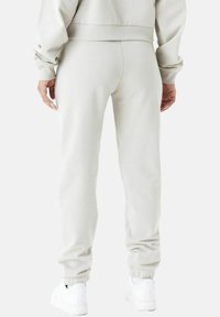 Helle graue Sweatpants aus weichem Material, mit elastischen Bündchen und einer Kordelzugbund. Glatte Textur und schlanke Passform.