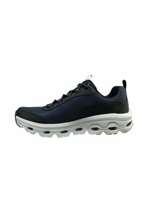 Scarpa sportiva in mesh nero con lacci neri e suola bianca spessa con molteplici fori d'aria per l'ammortizzazione.
