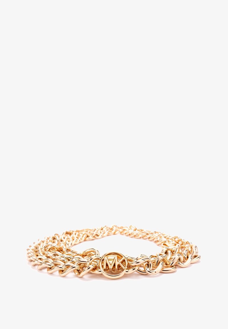 Collier chaîne ton or avec des maillons entrelacés et un fermoir circulaire avec le logo MK au centre sur fond blanc.