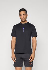 Zwarte sportieve t-shirt van zachte stof, met een paarse logo op de borst en contrasterende paarse accenten aan de zijkanten.