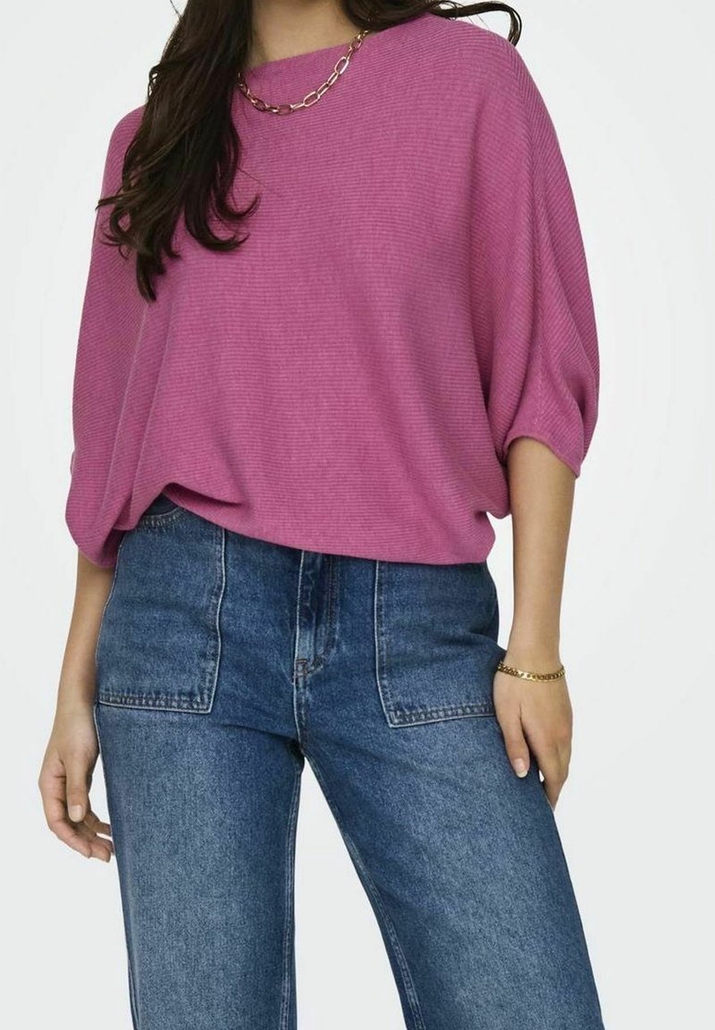 Top in magenta, morbido e a vestibilità ampia, con trama a coste e maniche corte a dolman, abbinato a jeans in denim blu a vita alta.