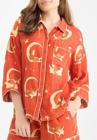 Rustfärgad pyjamas överdel med korta ärmar, prydd med ett tryck av en räv och månen, accentuerad med krämfärgad kant och knappar, samt en bröstficka.