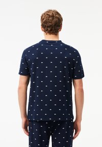 Marineblauwe t-shirt met korte mouwen van katoen, voorzien van een subtiel wit patroon op de hele kleding en een ronde hals.