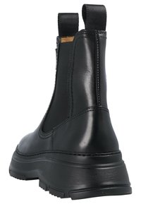Botas de tobillo de cuero negro con paneles elásticos en los laterales, suela de goma texturizada y tiradores para facilitar el calzado. Presenta costuras para mayor durabilidad.