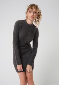 Flauschiges, dunkelgraues Strickkleid mit langen Ärmeln, hohem Ausschnitt, figurschmeichelndem Schnitt und weicher Textur, das bis zur Mitte des Oberschenkels reicht.