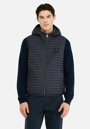 Navy puffervest med hætte, der har quiltet tekstur, lynlåslukning og sidelommer. Ribstrikkede ærmer skaber kontrast.