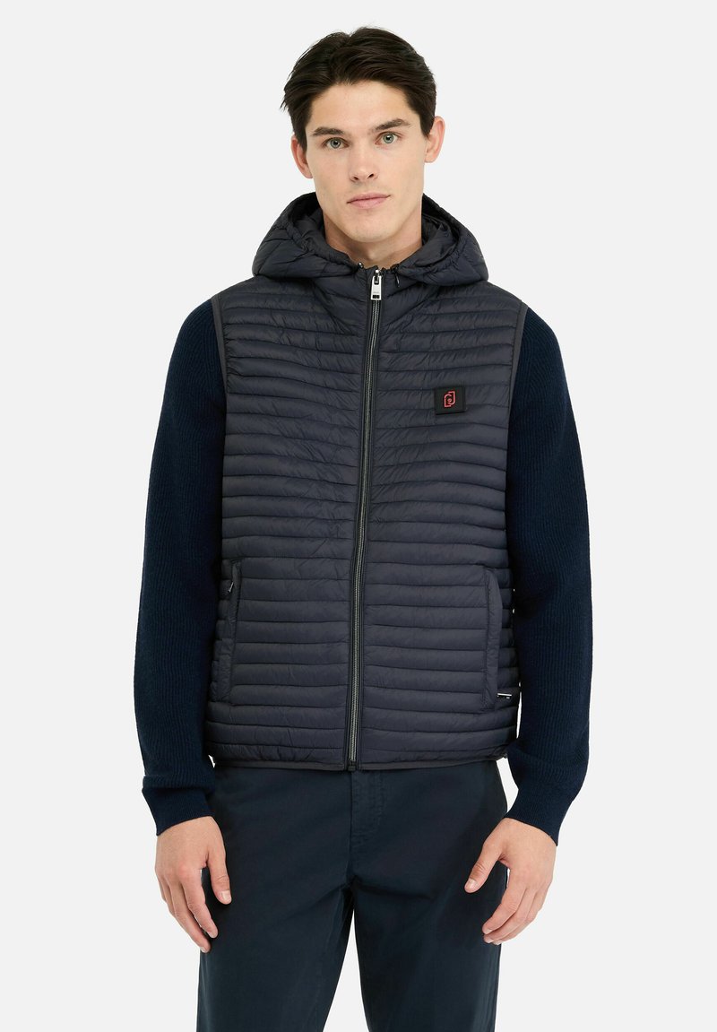 Doudoune sans manches bleu marine avec capuche, présentant une texture matelassée, une fermeture éclair et des poches latérales. Les manches en tricot côtelé ajoutent un contraste.