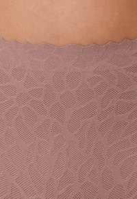Mauve textiel met een patroon van overlappende organische vormen en een golvende, gekartelde rand aan de bovenkant.