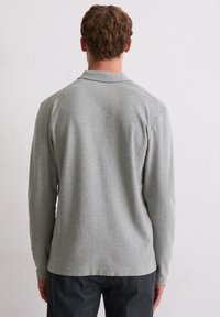 Langärmliges Poloshirt in Hellgrau, aus weicher Baumwolle gefertigt. Verfügt über einen klassischen Kragen und einen geraden Saum; keine sichtbaren Muster oder Verzierungen.