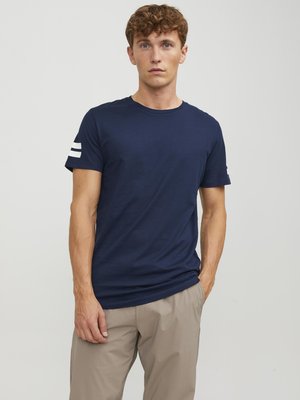 Camiseta de algodón azul marino con cuello redondo y mangas cortas. Presenta rayas blancas en la manga izquierda. Corte casual con una textura suave.