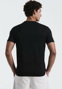 Zwarte katoenen t-shirt met korte mouwen en een ronde hals. Gladde textuur, slimfit ontwerp, en eenvoudig zonder patronen of accenten.