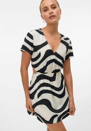 Robe courte en noir et blanc avec un décolleté en V, des manches courtes, une taille plissée et un motif abstrait ondulé. Présente des détails en découpe sur les côtés.