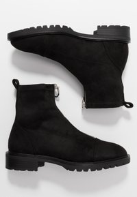 Bottines en suede noir avec une finition texturée, dotées d'un petit talon carré, de fermetures éclair latérales et de semelles en caoutchouc robustes.
