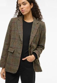 Houndstooth patterned blazer in brown, green, and burgundy tones. Features a notched lapel, single button closure, and side pockets.