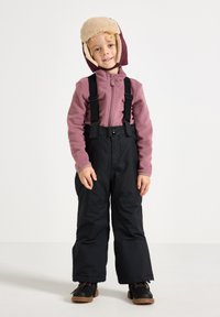 Barn iført en lilla fleecejakke og sorte snesække med justerbare stropper. En varmt foret mahognihat fuldender vinteroutfit.