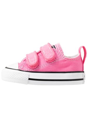 Zapatillas de lona rosas con dos correas de Velcro, puntera de goma blanca y línea negra a lo largo de la suela. Presenta un lazo en la parte trasera para facilitar el uso.