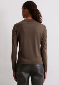 Bruine lange mouwen top van zacht materiaal, met een eenvoudig ontwerp en ribbelkraag, gecombineerd met slanke zwarte broek.